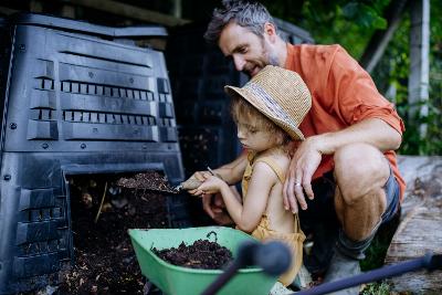 Father and daughter getting compost out of plastic compost bin